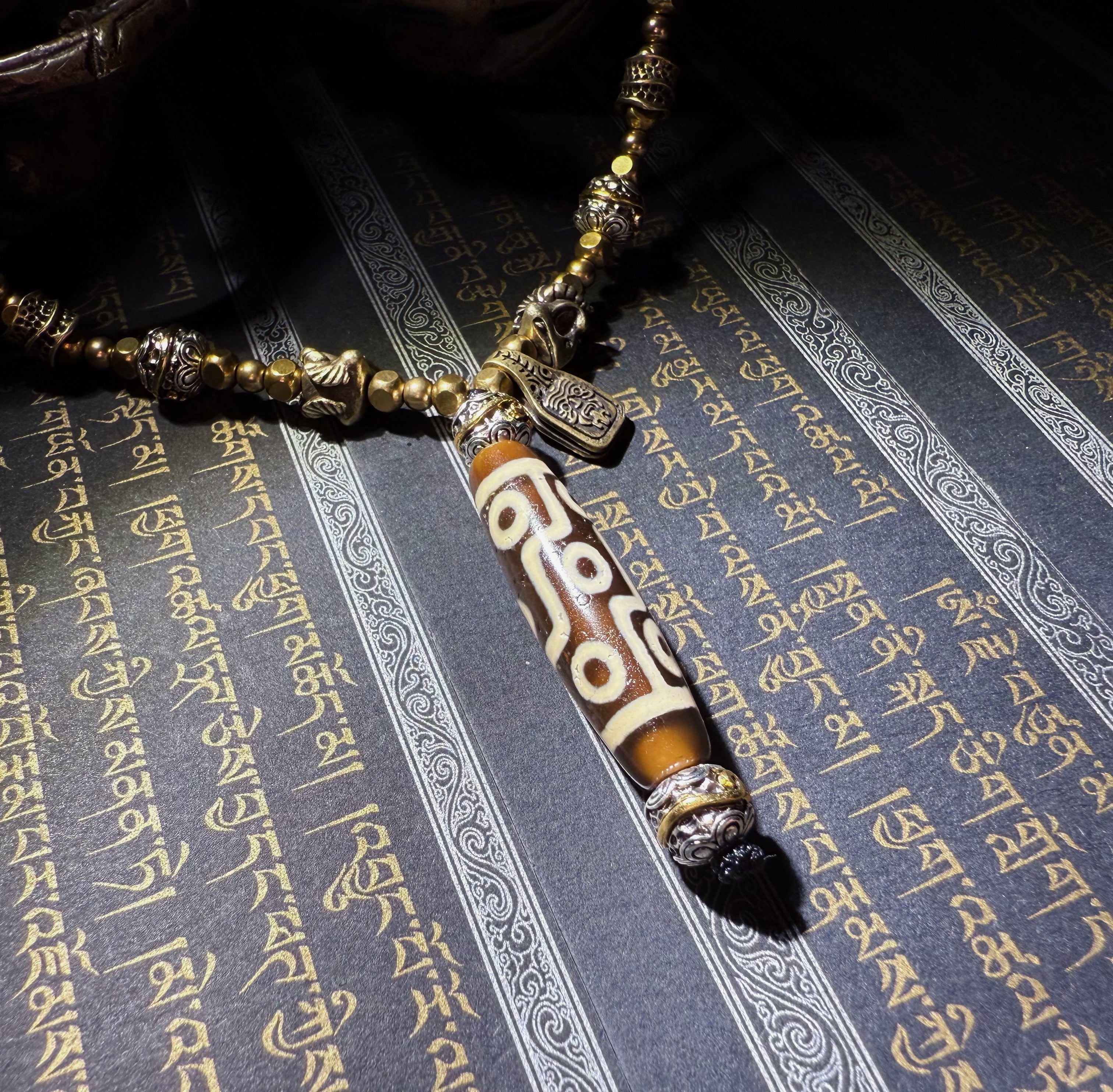 Tibetan Talisman — Handcrafted. Dzi bead necklaces and bracelets, prayer beads, thangkas, and ritual objects.This Dzi bead talisman necklace is an exceptionally beautiful, entirely handcrafted piece by Tibetan artisans, believed to hold powerful energy.