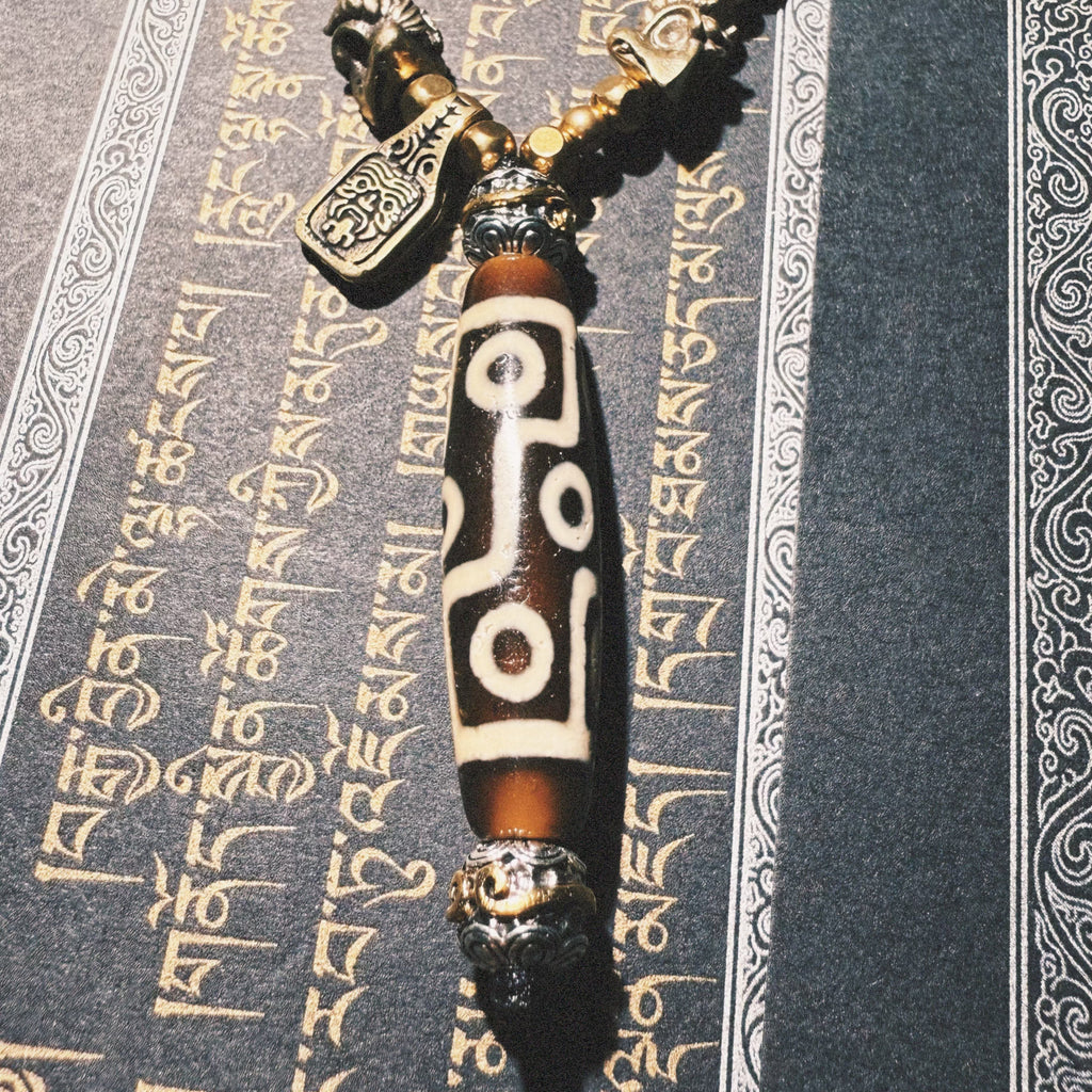 Tibetan Talisman — Handcrafted. Dzi bead necklaces and bracelets, prayer beads, thangkas, and ritual objects.This Dzi bead talisman necklace is an exceptionally beautiful, entirely handcrafted piece by Tibetan artisans, believed to hold powerful energy.