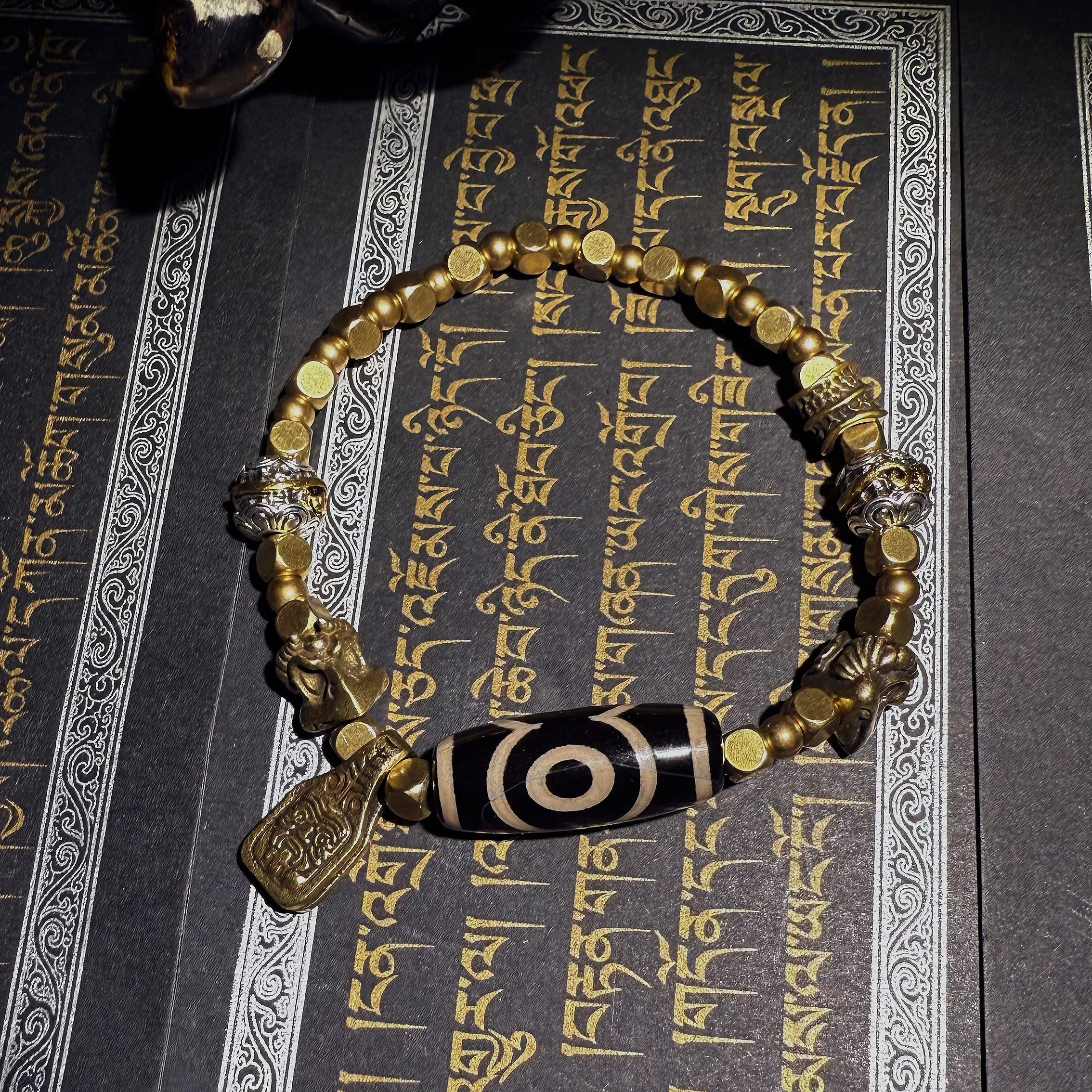 Tibetan amulets – handmade. Includes dzi bead necklaces, bracelets, prayer beads, thangkas, and ritual implements. This dzi bead amulet bracelet is exquisitely handcrafted by Tibetan artisans and is believed to contain powerful energy.