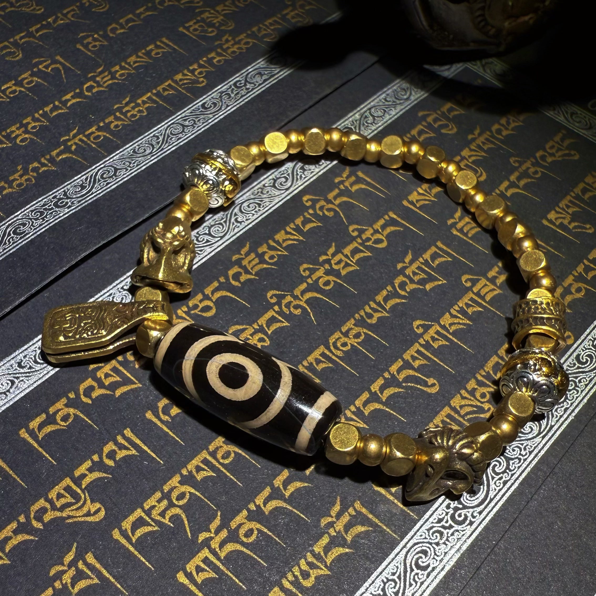 Tibetan amulets – handmade. Includes dzi bead necklaces, bracelets, prayer beads, thangkas, and ritual implements. This dzi bead amulet bracelet is exquisitely handcrafted by Tibetan artisans and is believed to contain powerful energy.