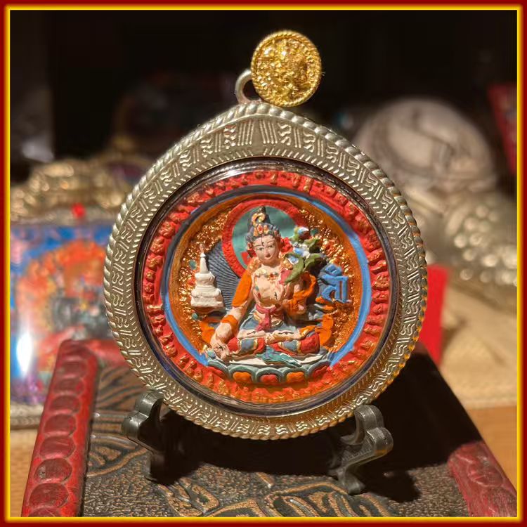This is a Buddha amulet made of clay by artisans on the roof of the world, fired at high temperatures, and hand-painted with mineral pigments. Its name is White and Green Tara.