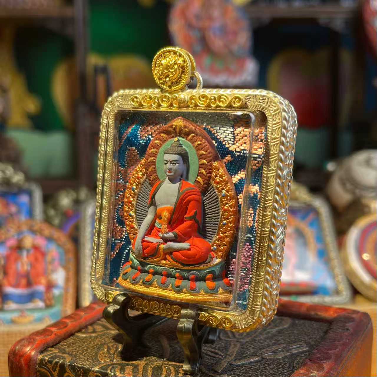This is a Buddha amulet made of clay by artisans on the roof of the world. It was fired at high temperatures and then hand-painted with mineral pigments. Its name is Akshobhya Buddha.