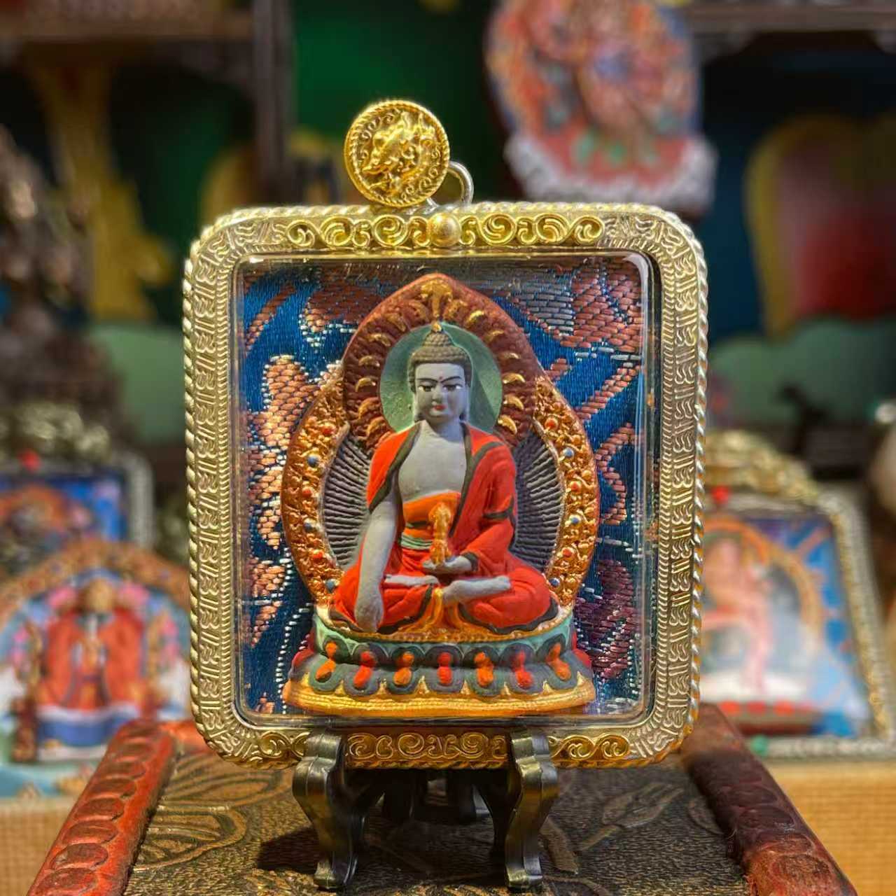 This is a Buddha amulet made of clay by artisans on the roof of the world. It was fired at high temperatures and then hand-painted with mineral pigments. Its name is Akshobhya Buddha.