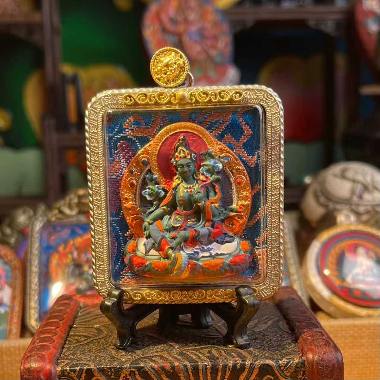 This is a Buddha amulet made of clay by artisans on the roof of the world, fired at high temperatures, and then hand-painted with mineral pigments. Its name is Green Tara.